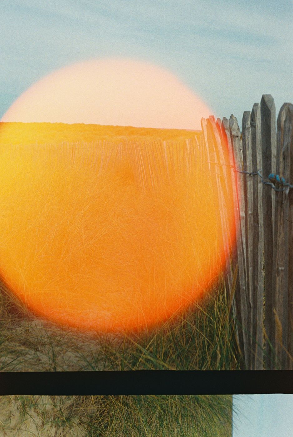 A wooden fence with an orange light flare